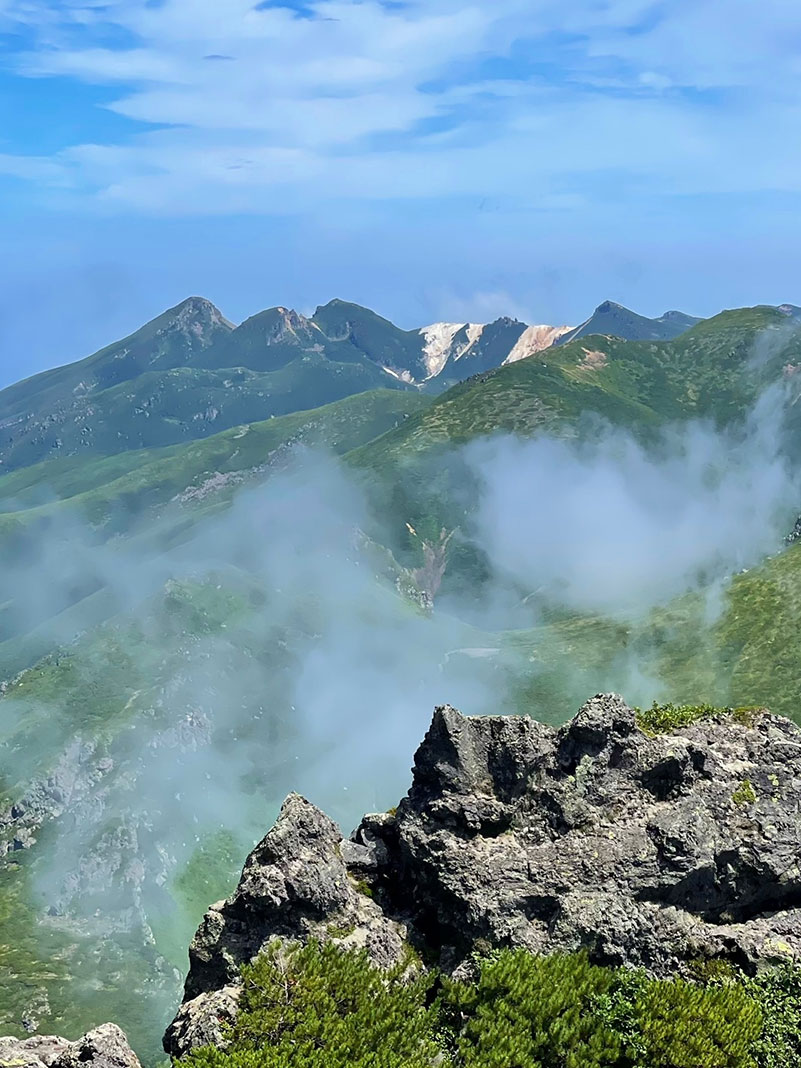 Looking off a mountain peak with clouds.