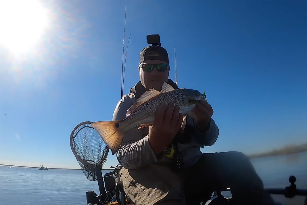 kayak angler holds up a Texas redfish