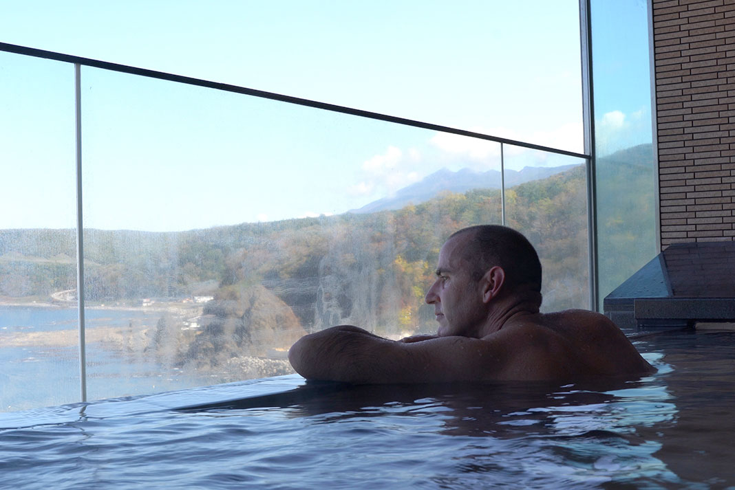 Man gazes out at water from a hot spring pool
