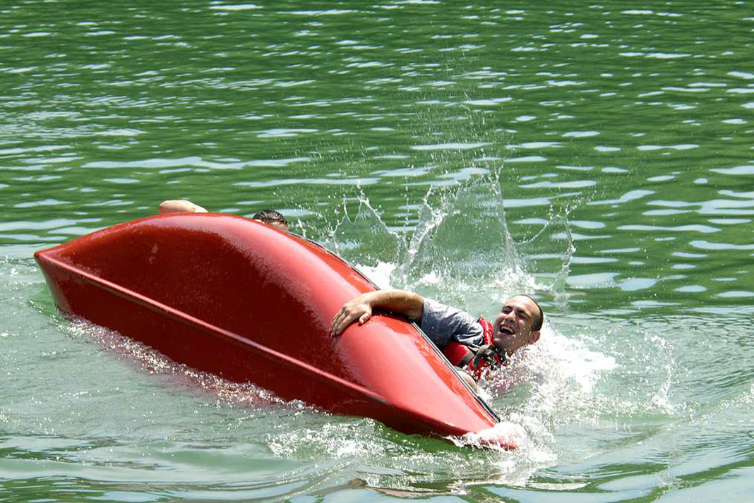 man holds on to capsized canoe prior to a rodeo canoe rescue