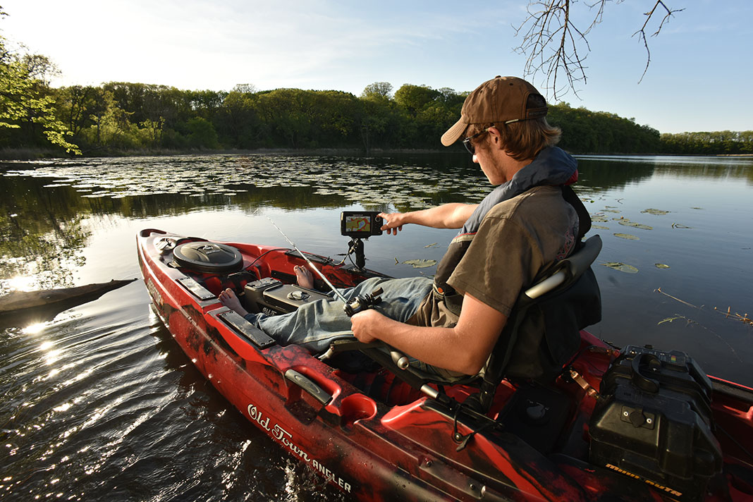 man on fishing kayak uses a fish finder