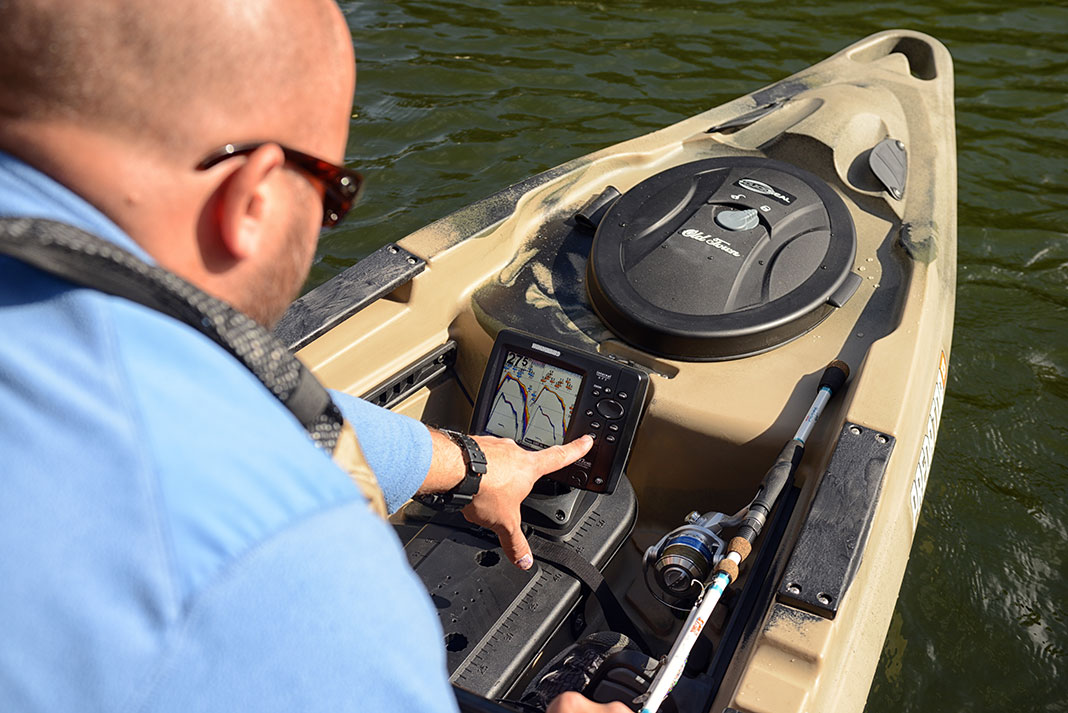 man presses the buttons on his fish finder