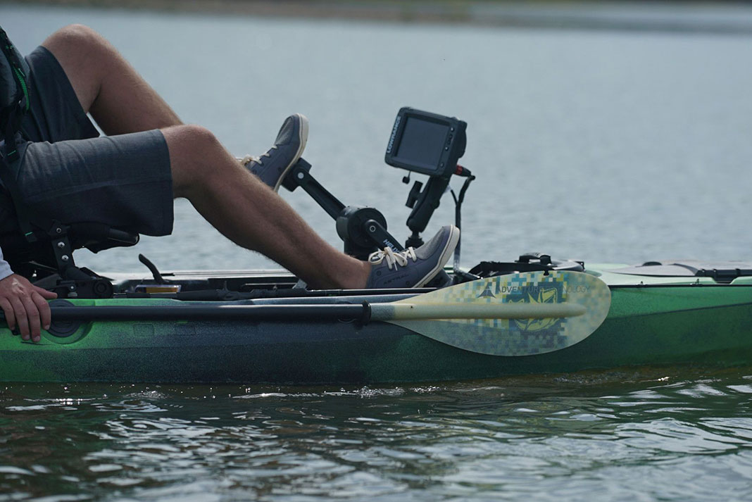 angler pedals a fishing kayak equipped with a fish finder