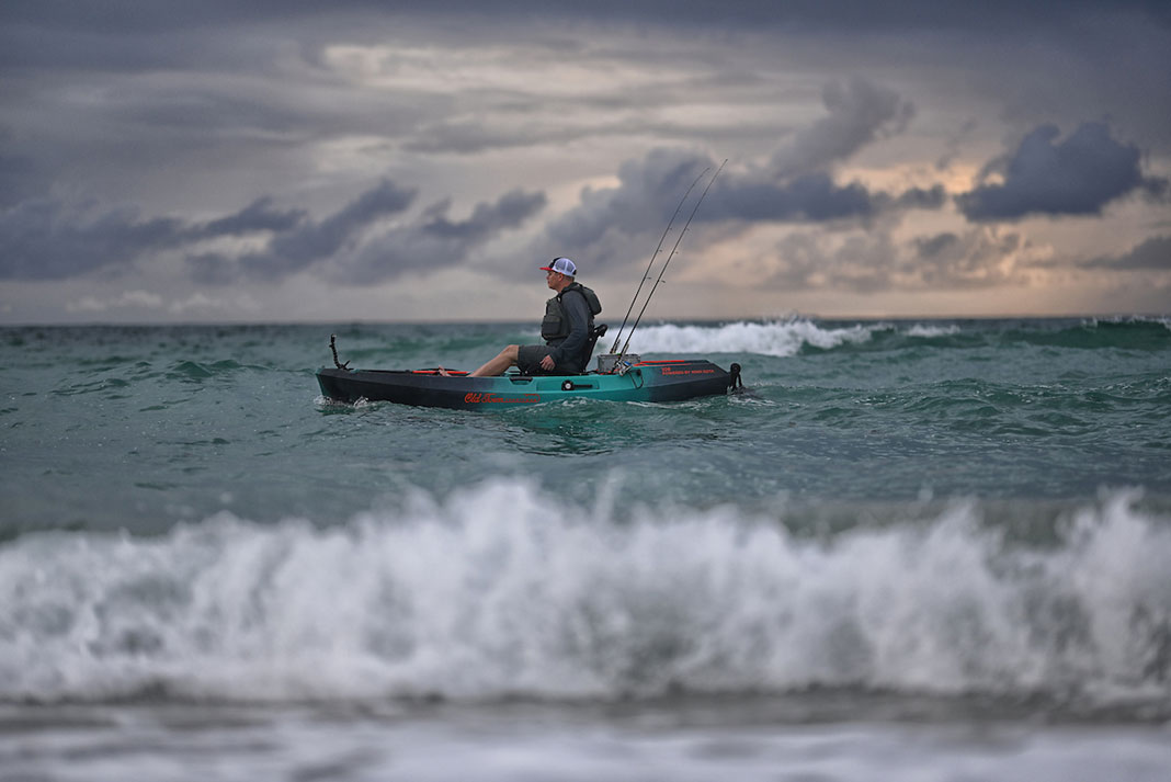 man pedals Old Town fishing kayak just beyond the surf