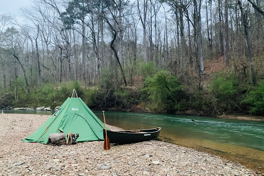 canoe and tent pitched beside Alabama river