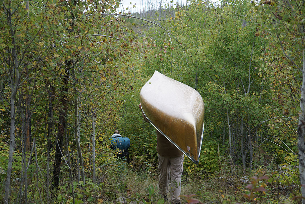 people portage an ultralight canoe through a forest