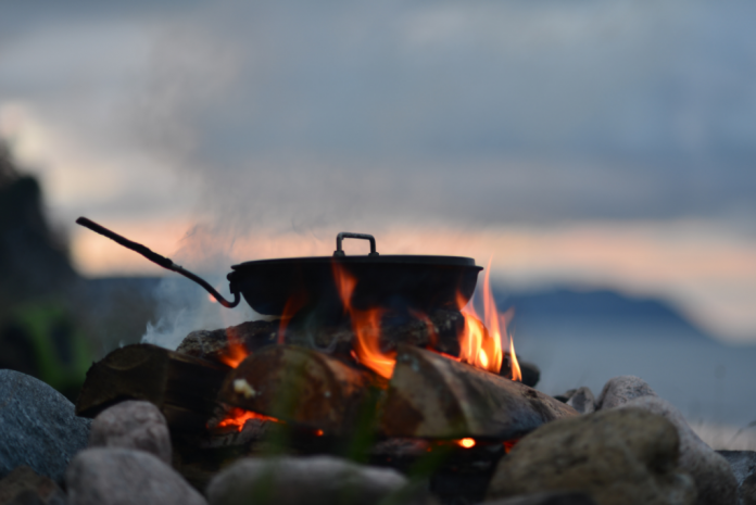 dinner cooking in a pot over an open fire outside