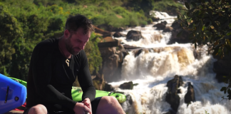 whitewater kayakers paddle down a river that weaves through thick jungle in kenya
