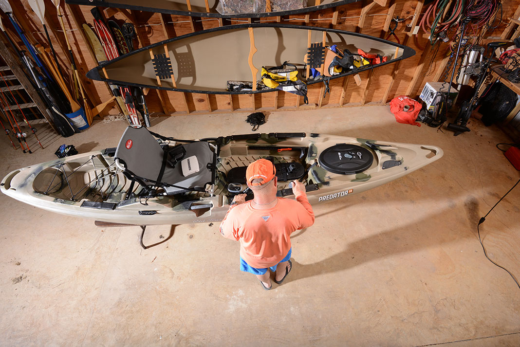 man works on his fishing kayak in a workshop