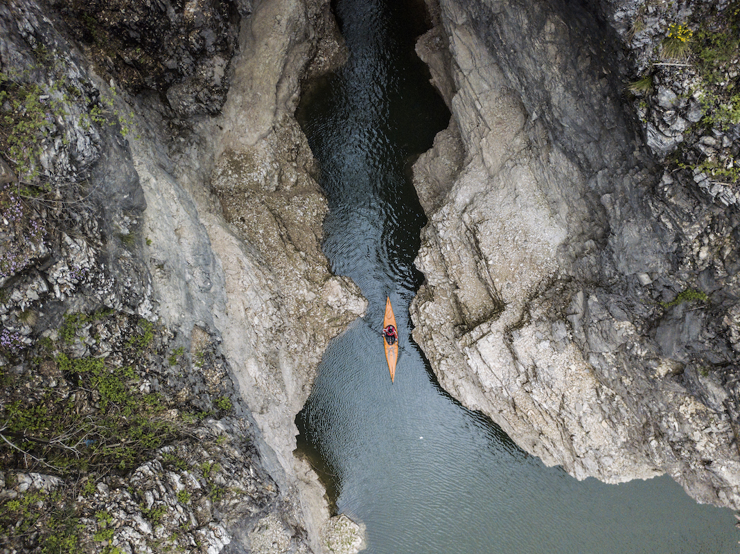 Overhead shot of inflatable kayak being paddled between two cliffs