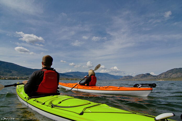 Two people paddling green and orange touring kayaks
