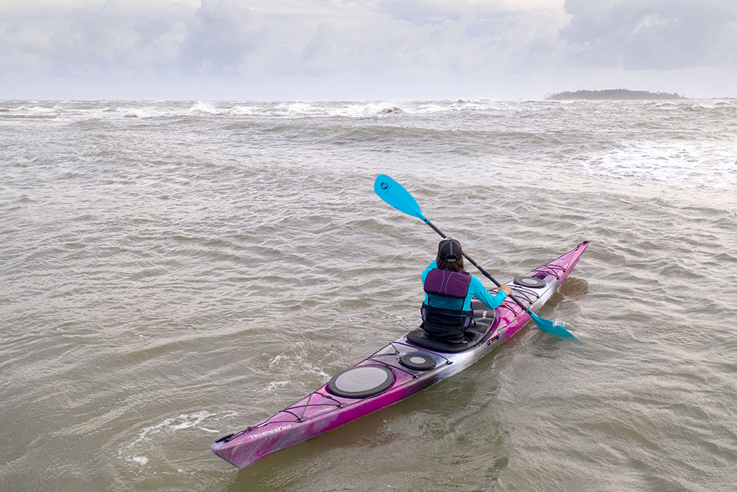 Woman paddling purple touring kayak
