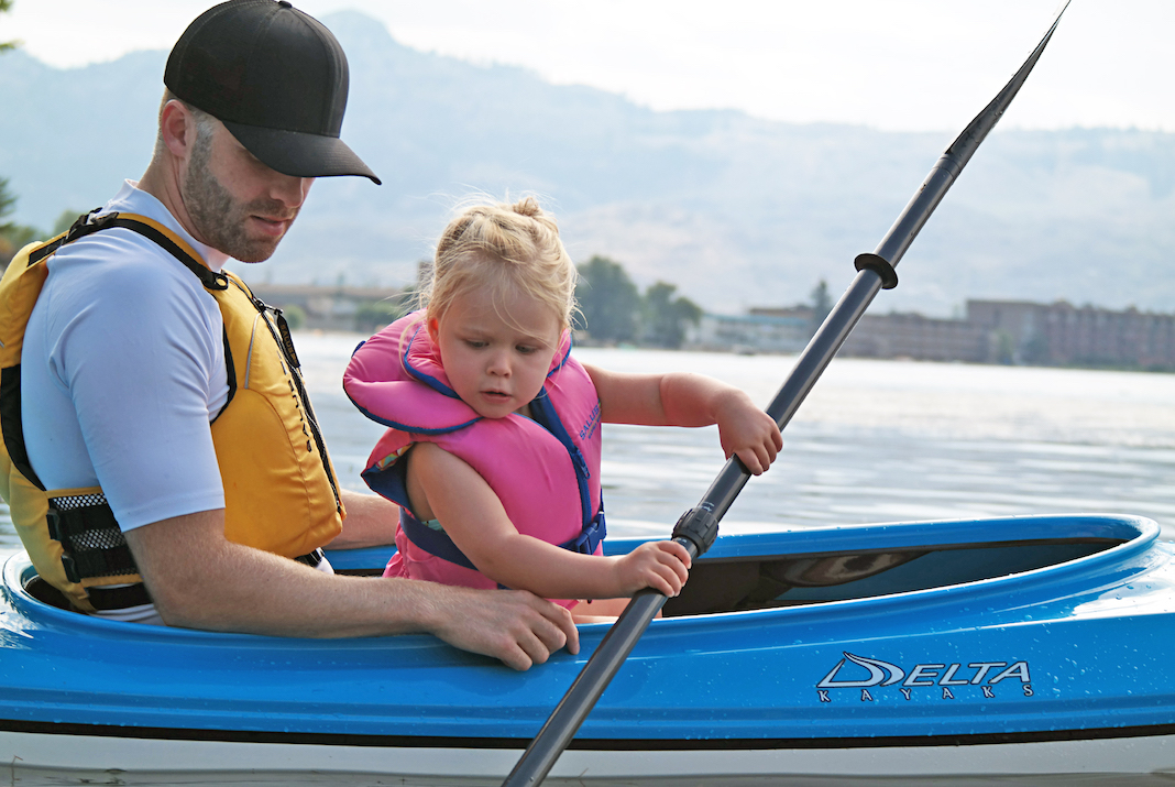 Man and little girl paddling blue kayak