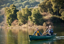 Two people paddling dark green canoe