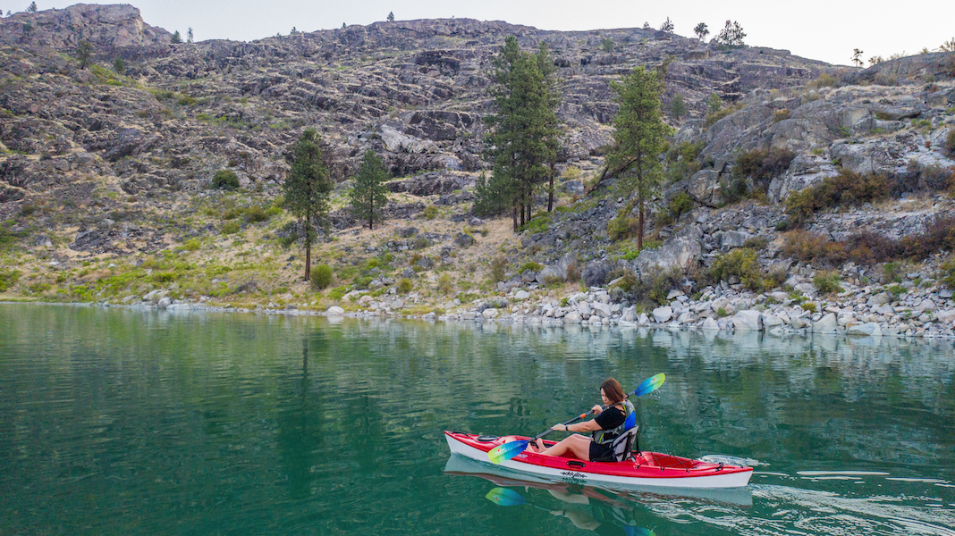 Woman paddling kayak on green-colored waters