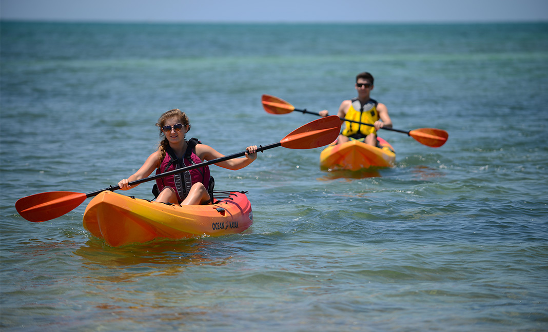Man and woman paddling separate orange sit-on-top kayaks