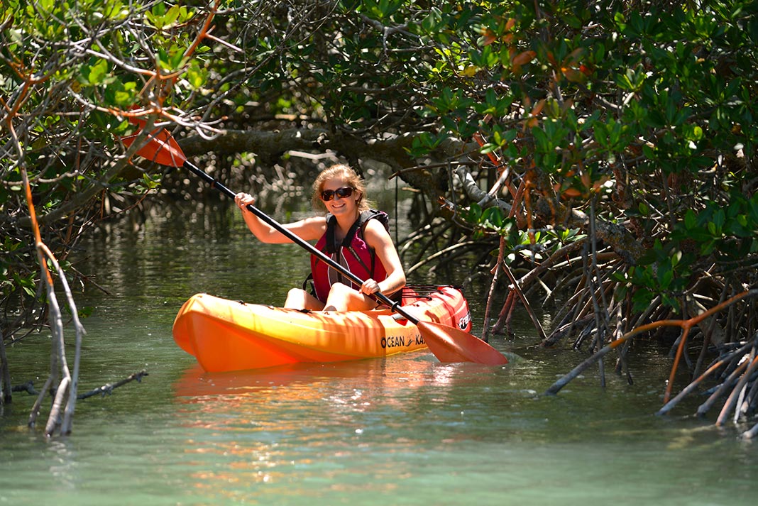 Woman paddling orange sit-on-top kayak