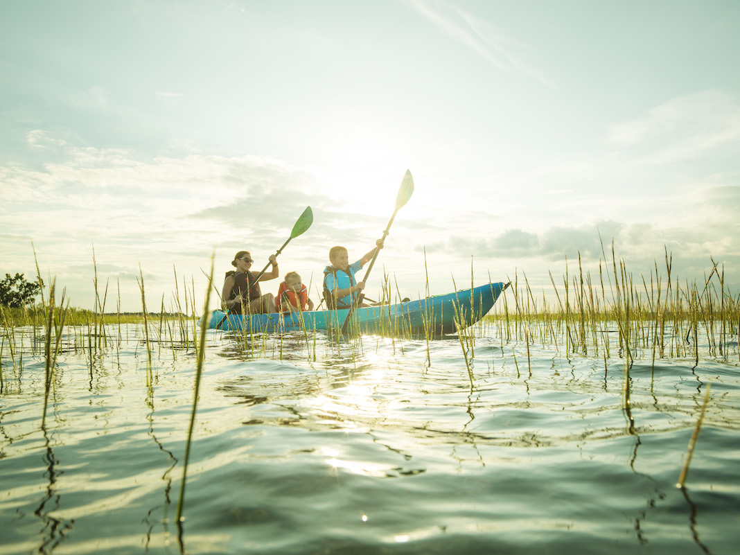 Parent and two kids paddling on sit-on-top kayak