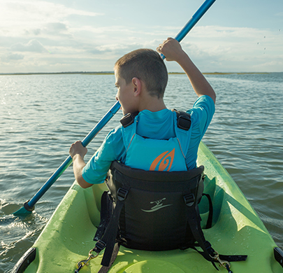 Boy paddles in bow seat of tandem kayak