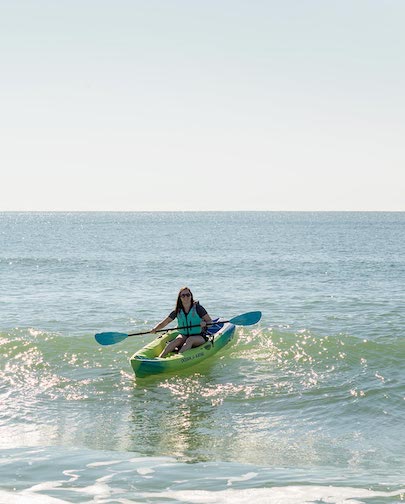 Woman riding a wave on a green kayak