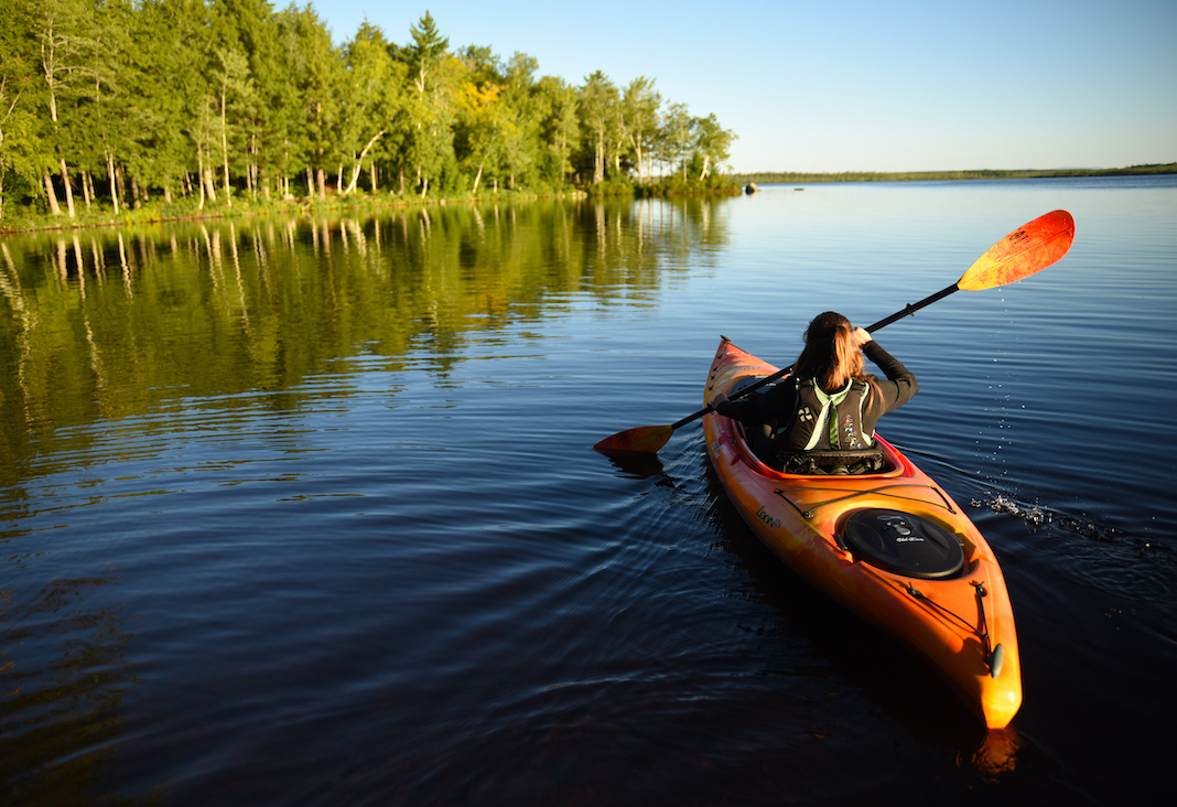 Woman paddling orange touring kayak