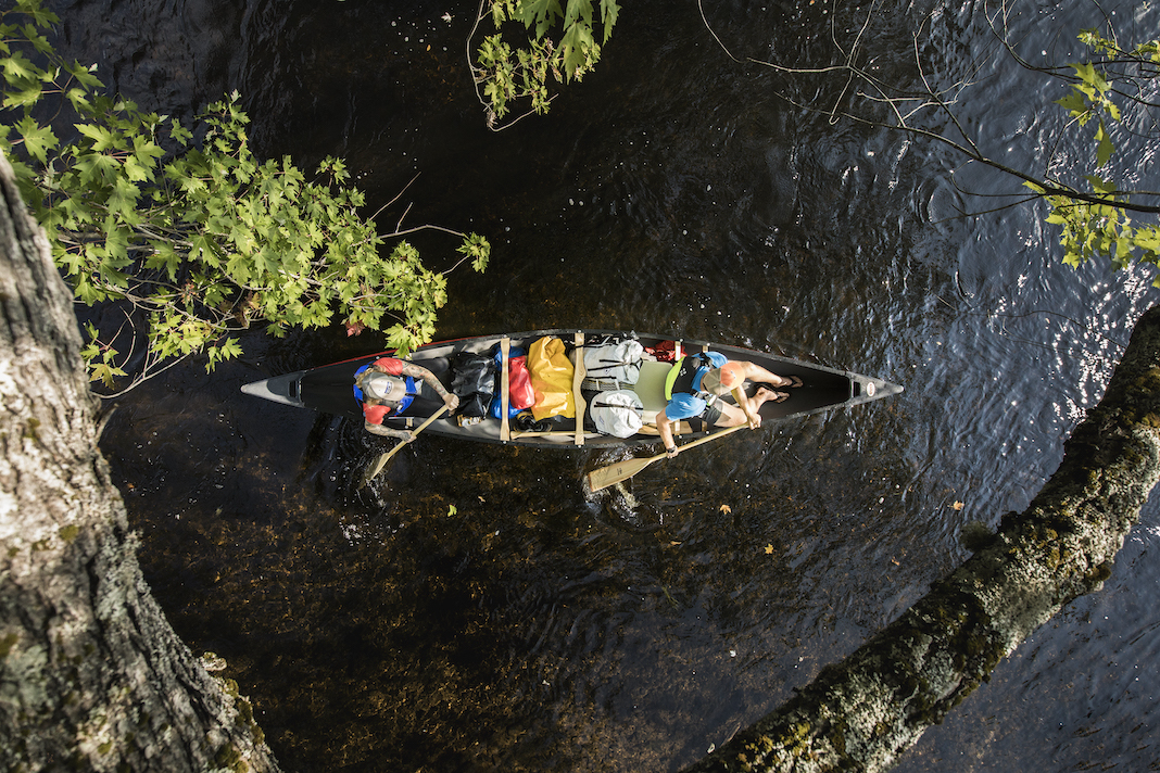 Overhead shot of two people paddle canoe fully loaded with gear