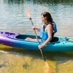 Recreational Kayak Review: Perception Swifty Deluxe 9.5 Woman paddling sit-inside green, blue and purple kayak