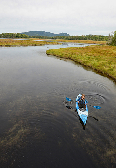 Person paddling recreational kayak on winding river