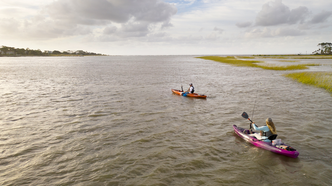 Two kayaks being paddled on wavy waters 