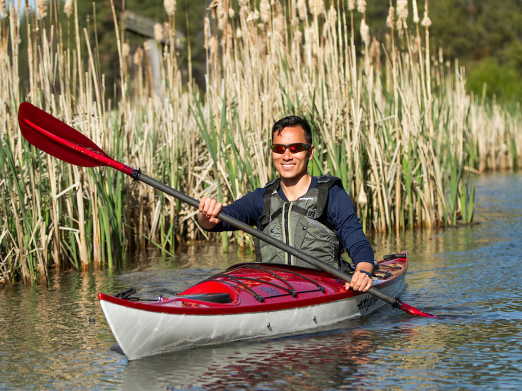 Man paddling red and white kayak