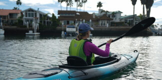 Woman paddling blue and black sit-in kayak