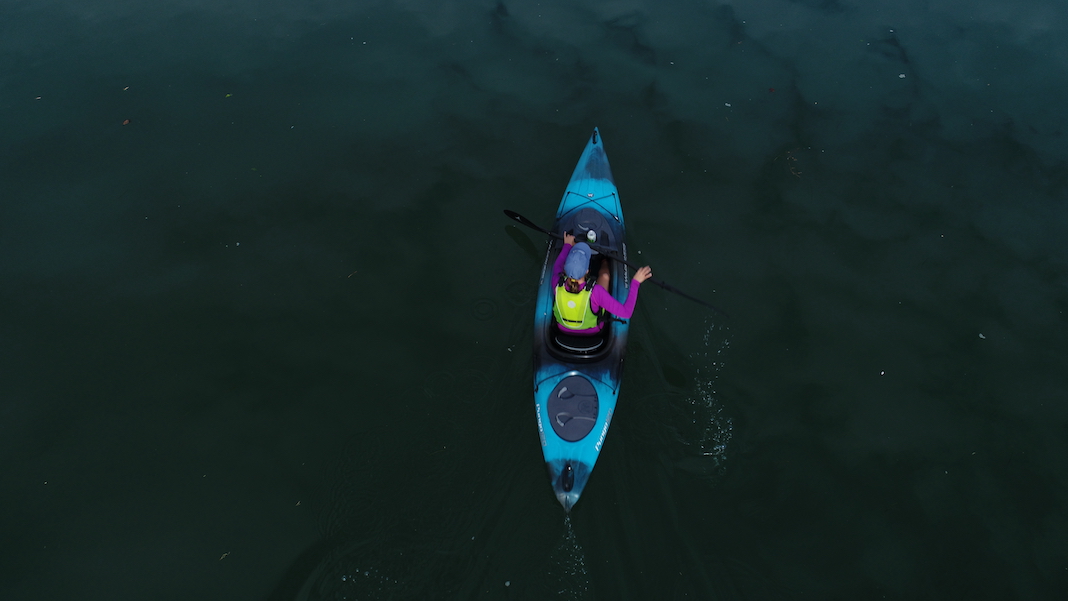 Overhead shot of woman paddling black and blue kayak