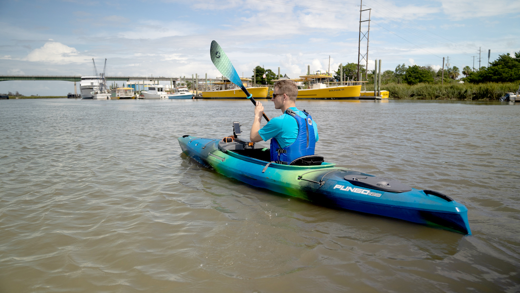 Man paddling blue and green kayak