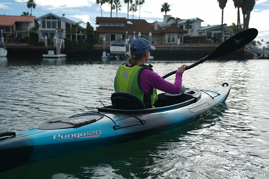 Woman paddling blue and black sit-in kayak