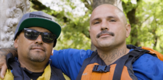 Two male ex-gang members stare happily at the camera while wearing rafting gear.