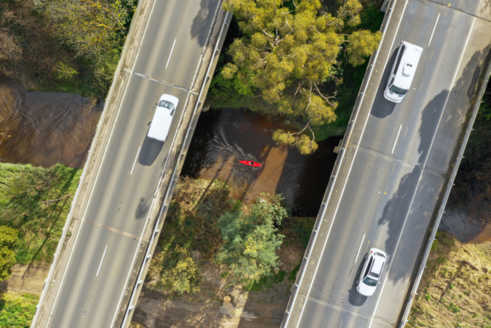 man kayaks under bridge