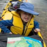 kid poses in a kayak with map