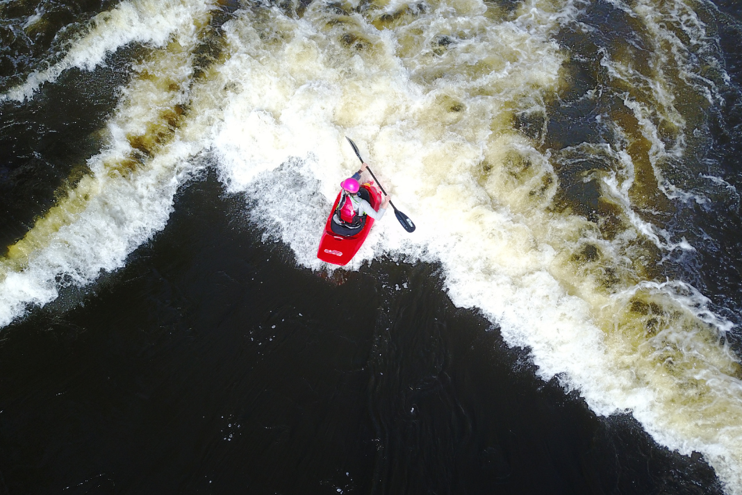 whitewater kayaker surfs wave