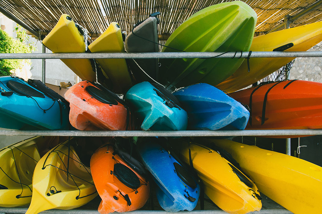 Three rows of kayaks on racks with different shaped hulls.