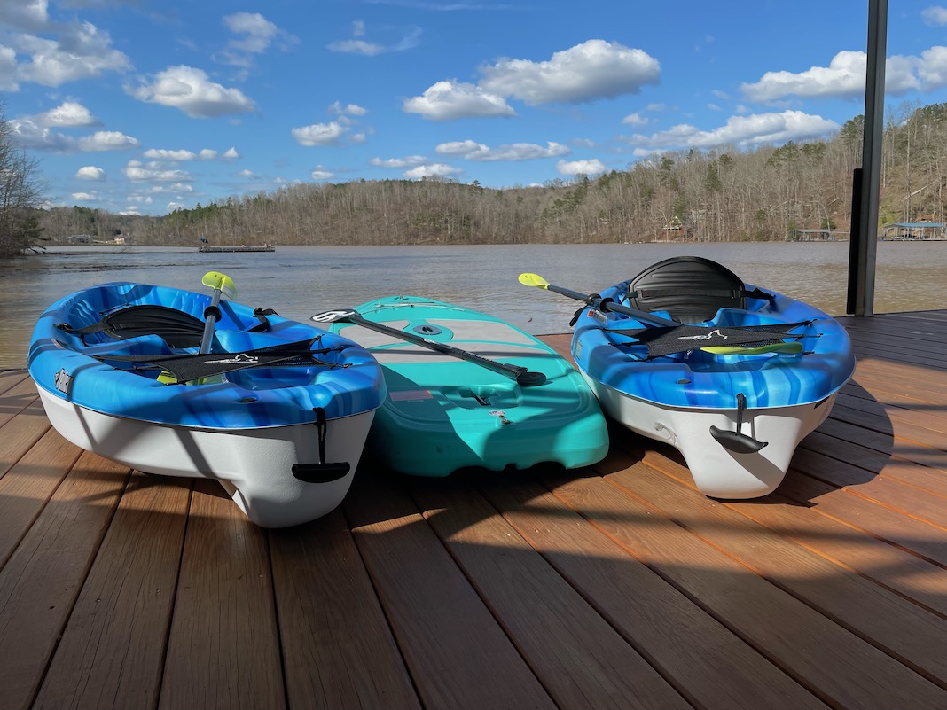 Two kayaks and a paddleboard sitting on a dock