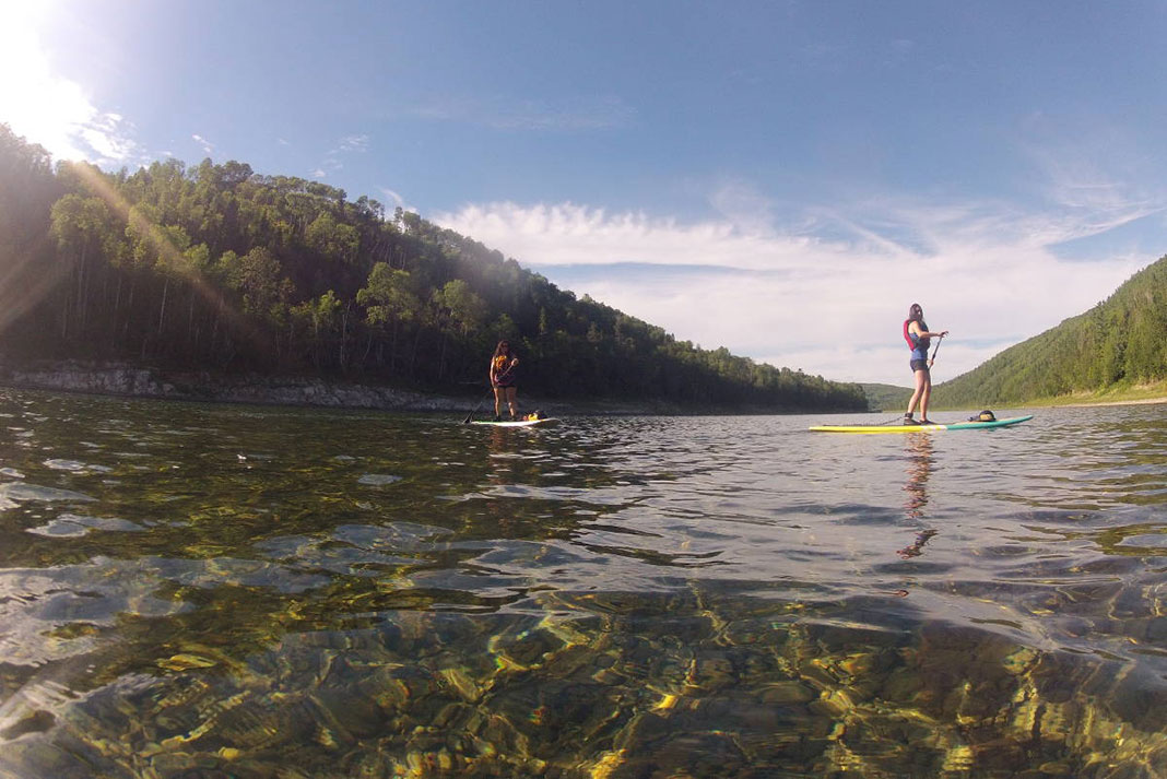 two women SUP on a river with very clear water