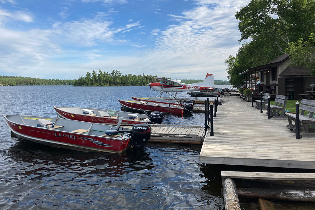 motorboats and float plane sit at dock by Boundary Waters accommodations