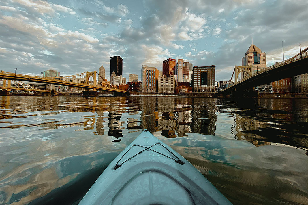 bow shot from a kayaker paddling in front of an urban skyline