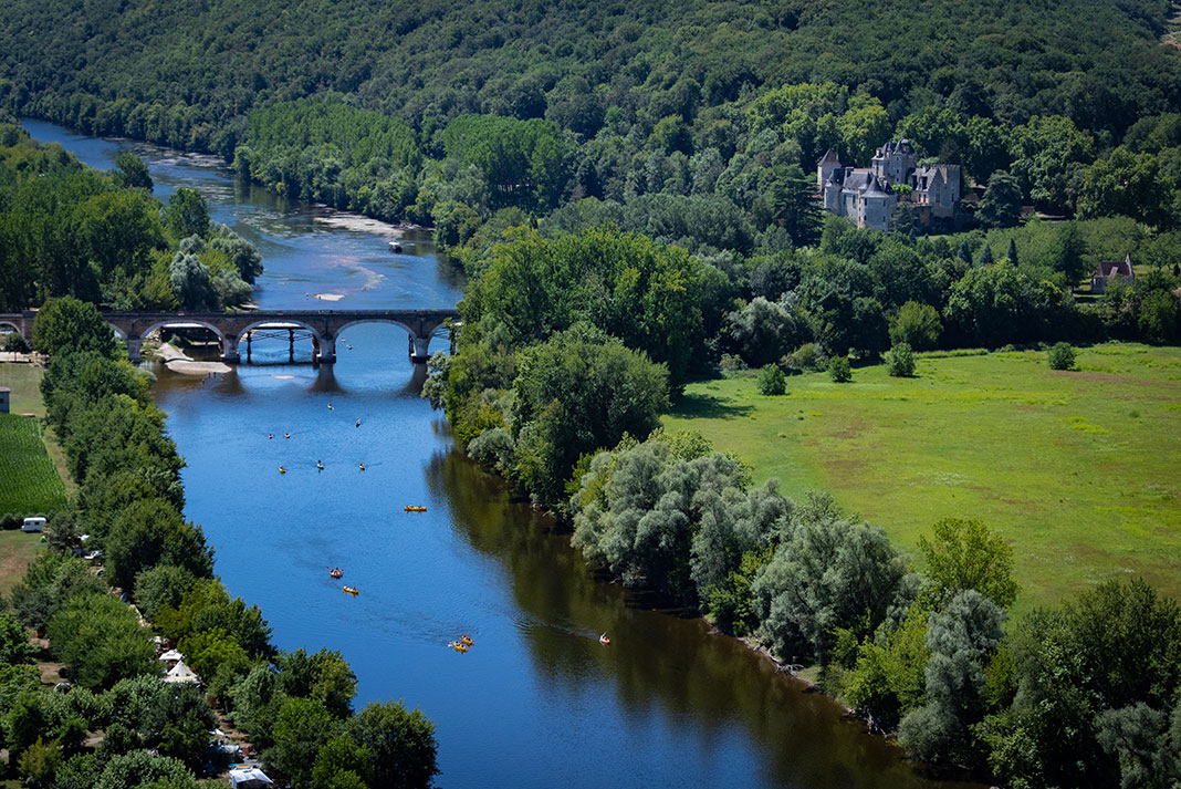 a group of kayakers paddle down the Dordogne River in France in summer on the trip of a lifetime
