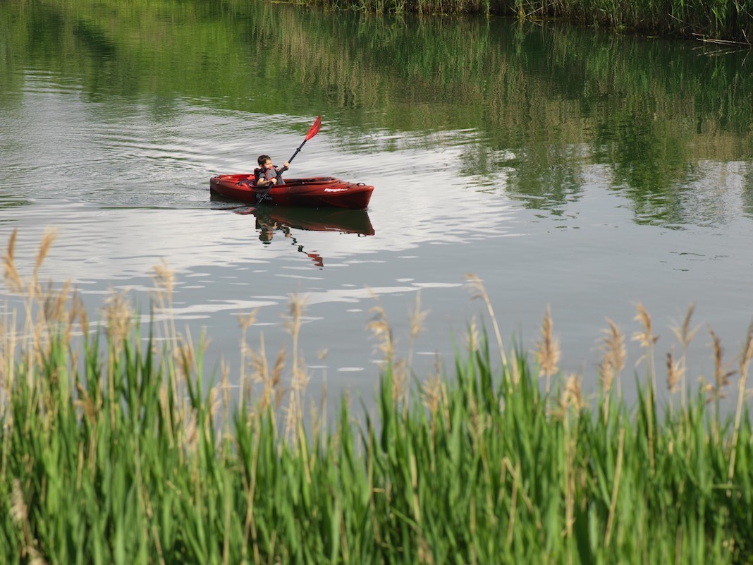 Child paddling red sit-inside kayak