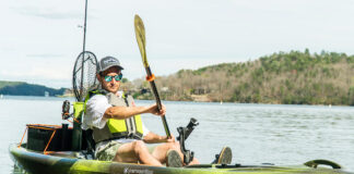 Man paddling green and grey sit-on-top fishing kayak