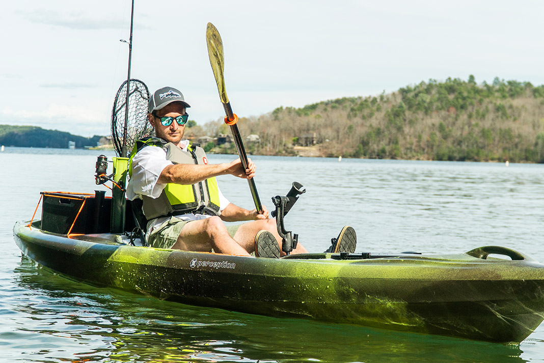 Man paddling green and grey sit-on-top fishing kayak