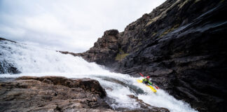 man whitewater kayaks along a narrow, rocky Arctic river