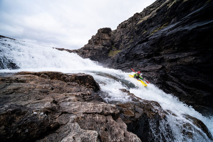 man whitewater kayaks along a narrow, rocky Arctic river