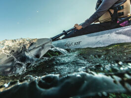 Grey sit-on-top fishing kayak being paddled on wavy waters
